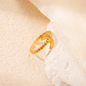 Dettaglio anello a sfere dorato con simbolo della luna su una superficie di pietra