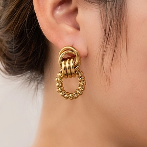 Macro shot of layered gold earrings with mixed smooth and beaded textured metallic rings