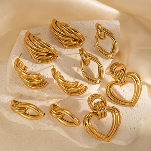 Detailed arrangement of gold geometric earrings and heart pendants on stone pedestal