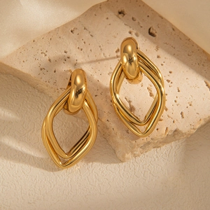 Close-up of geometric gold-plated titanium earrings on natural stone and silk fabric