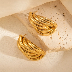 Detail of five-layer gold titanium steel hoop earrings on stone and silk background