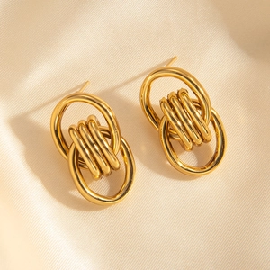 Detailed macro view of gold-plated stainless steel earrings on beige silk background
