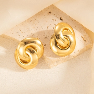 Macro shot of gold-plated twisted hoop earrings displayed on a textured stone base