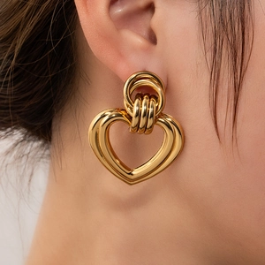 Close-up of gold hollow heart-shaped titanium earrings worn on a model ear