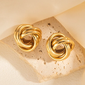 Close-up of gold multi-layer knotted stud earrings on a stone display stand