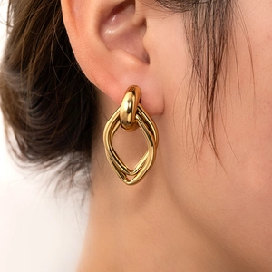 Detail view of intertwined golden geometric rings on ear with polished finish