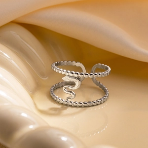 Détail d'une bague serpent argentée à doubles anneaux perlés sur un fond en satin