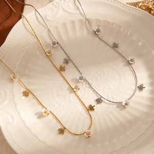 Elegant gold and silver titanium steel necklaces with flower charms on a vintage plate