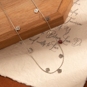 Macro detail of silver rose pendant necklace on vintage paper and wood display