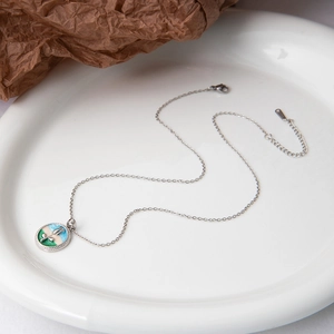Détail du collier en argent S925 avec pendentif en émail coloré dans un bol en céramique