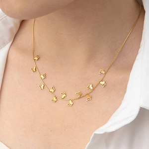 Detail of elegant gold-tone necklace with multiple hollow butterfly pendants on neck