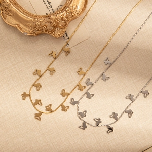 Elegant gold and silver titanium necklaces with hollow butterfly charms on beige fabric