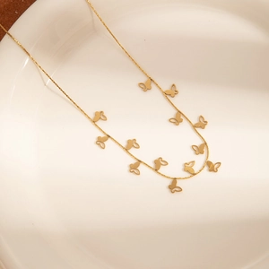 Detailed view of golden butterfly charms on a delicate chain in a white ceramic dish