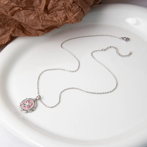 Détail macro du collier rétro français avec pendentif fleur en émail rose et perle