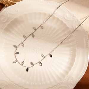Detail of silver leaf pendant necklace on white ceramic tray with vintage frame