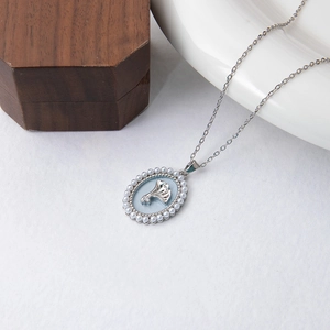 Détail du pendentif feuille de ginkgo argenté avec émail bleu et bordure en perles