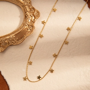 Macro detail of a gold titanium necklace with hollow butterfly and rose star pendants