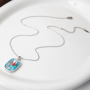 Détail du collier pendentif en émail avec fleurs de rose et ginkgo et perles blanches