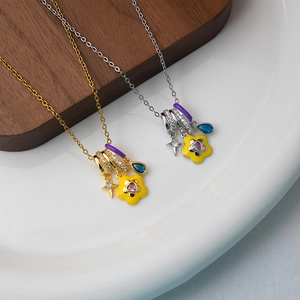 Close-up of gold and silver necklaces featuring enamel flowers and crystal star charms