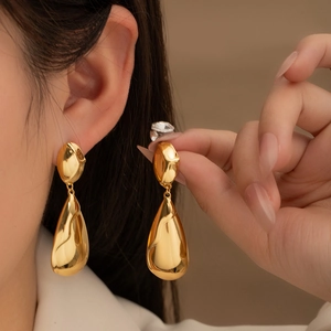 Pendientes de gota en acero de titanio dorado con un diseño de metal fluido