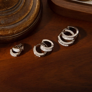 Three sizes of polished silver hoop earrings with pave cubic zirconia on a wooden surface