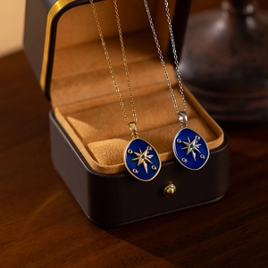 Detailed macro of gold and silver starry sky enamel compass pendants on titanium necklaces