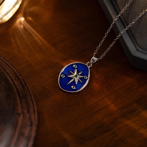 Detail of vintage starburst pendant with blue enamel and silver compass on wood