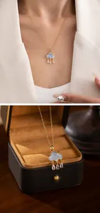 Detail view of gold cloud pendant with blue texture and zircon tassels on a model