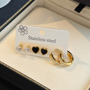 Three pairs of stainless steel earrings with heart, zircon, and hoop designs in gold