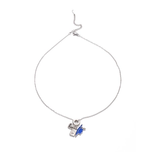 Close-up of silver necklace with blue graduation cap, passport, and black heart charms