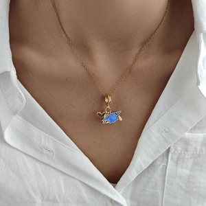 Gold heart and blue graduation cap pendant necklace worn over white linen shirt