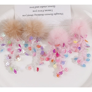 Dettaglio orecchini con pompon rosa e lunghe nappe di perline con faccine sorridenti