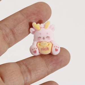 Vue macro d'une petite breloque dragon rose floquée tenant un lingot d'or avec texte