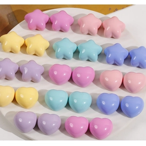 Macro detail of colorful glossy star and heart resin charms in a white ceramic dish