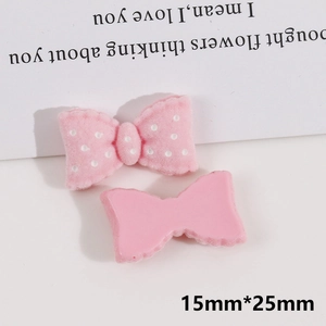 Detail view of 15x25mm pink bow resin charms with flocking and polka dot textures