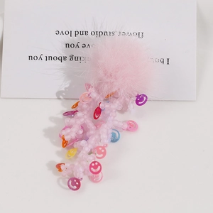 Dettaglio sfera di peluche rosa con nappe di perline e ciondoli smiley colorati