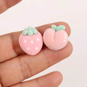 Close-up of pink flocked strawberry and peach resin charms for DIY jewelry making