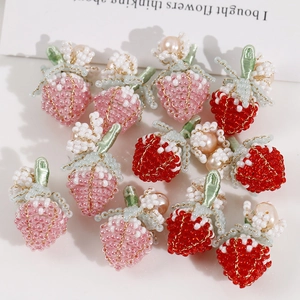 Dettaglio di ciondoli a forma di fragola fatti a mano con piccoli fiori e perle
