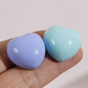 Macro shot of 2cm heart-shaped resin charms in pastel blue and purple for DIY hair accessories