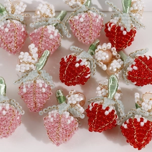 Dettaglio di fragole fatte a mano con perle d'acqua dolce intrecciate e fiori rosa