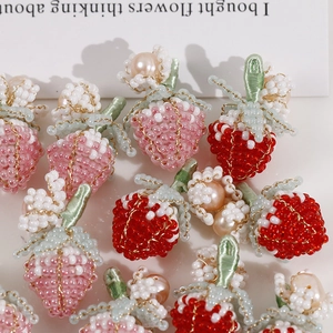 Dettaglio di fragole intrecciate a mano con perle d'acqua dolce e steli verdi