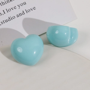 Close-up of light blue glossy resin heart and round charms on a white decorative tray