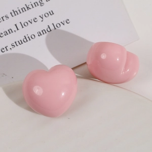 Close-up of pink heart-shaped resin stud earrings with a glossy polished finish