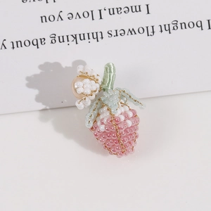 Dettaglio di ciondolo fragola fatto a mano con perle rosa e piccolo fiore decorativo
