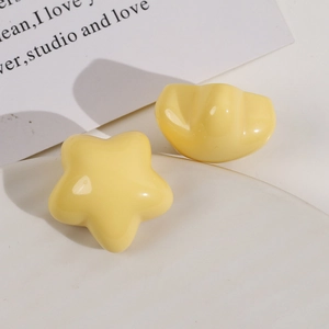 Macro shot of glossy yellow star and heart-shaped resin charms on a white background