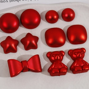 Red bow, star, and bear acrylic charms for DIY hair clips displayed on a white plate