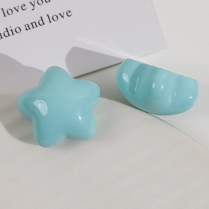 Macro shot of two glossy light blue resin star and heart-shaped charms for hair DIY accessories