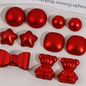 Red matte acrylic charms set with stars, bears, and bows on a white tray for DIY crafts