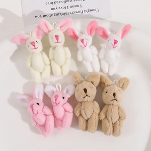 Macro detail of colorful plush bunny pendants with embroidered faces in a ceramic dish