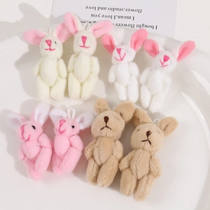 Plush cartoon bunny pendants in four soft colors displayed on a white ceramic plate
